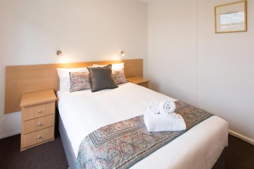 a bedroom with a large white bed with a wooden headboard at Fox on the Run - Motel Kilmore in Kilmore