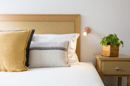 a bed with pillows and a plant on a night stand at Fox on the Run - Motel Kilmore in Kilmore