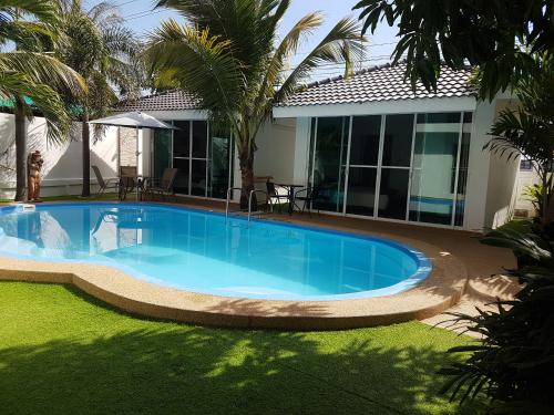 a swimming pool in front of a house at Coconut Palms in Kantharawichai