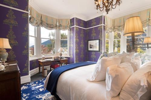 a bedroom with purple walls and a bed with white pillows at Hulbert House Luxury Boutique Lodge Queenstown in Queenstown