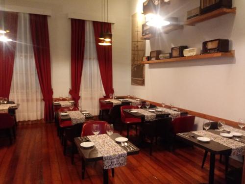 a dining room with tables and chairs and red curtains at Hotel Baquedano Boulevard in Iquique