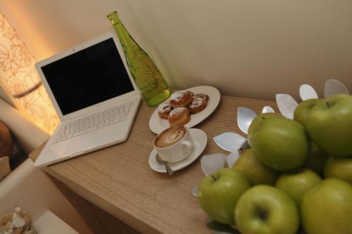un tavolo con un computer portatile, una tazza di caffè e delle mele di Hotel Principe a Rimini