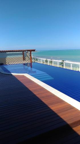 a deck with a bench and the ocean in the background at FLAt COMPLETO BEIRA MAR in Cabedelo