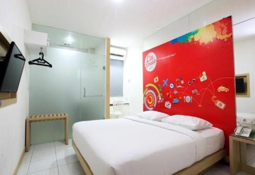 a bedroom with a white bed and a red wall at Citismart Hotel Pekanbaru in Pekanbaru