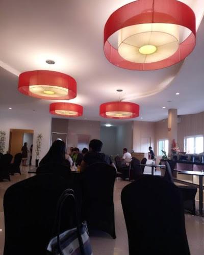 pessoas sentadas num restaurante com luzes vermelhas em Citismart Hotel Pekanbaru em Pekanbaru
