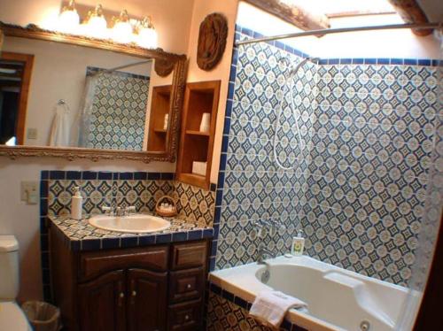a bathroom with a tub and a sink and a mirror at La Dona Luz Inn an Historic B&B in Taos
