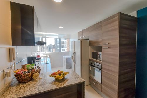 a kitchen with a counter with a bowl of fruit on it at Suite de Lujo, Piso Alto, junto Parque Carolina, Generador electrico in Quito