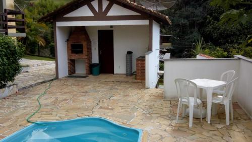 a patio with a table and chairs and a house at Charmoso com Sauna e Piscina in Penedo