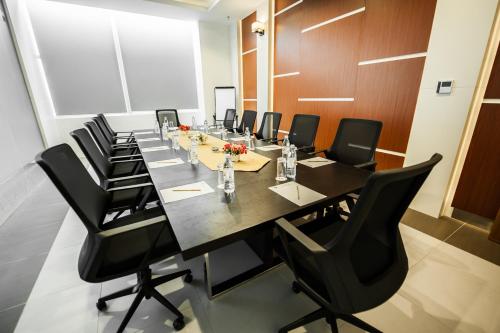 a conference room with a long table and black chairs at Garden Sentral Hotel in Kuala Belait