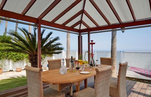 a wooden table and chairs on a patio with the ocean at Limassol Beachfront Holiday Villa in Limassol