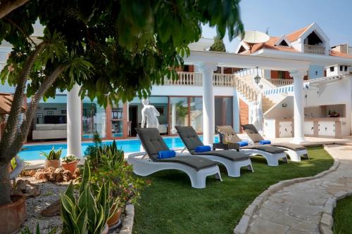 a yard with lounge chairs and a swimming pool at Limassol Beachfront Holiday Villa in Limassol