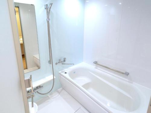 a white bathroom with a shower and a sink at La'gent Hotel Okinawa Chatan Hotel and Hostel in Chatan