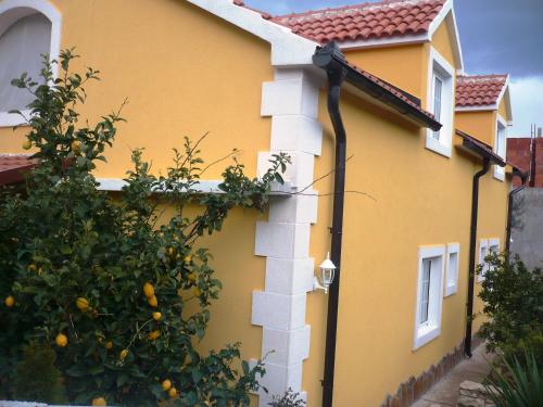 a yellow house with an orange tree next to it at Apartments Brač in Supetar