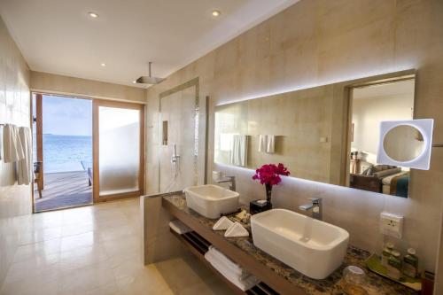 
a bathroom with two sinks and a large mirror at Hurawalhi Island Resort in Kuredu
