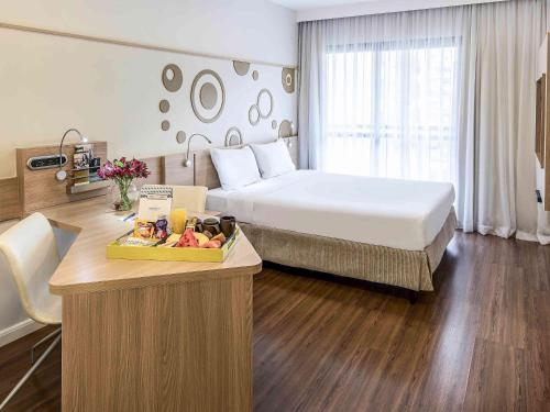 a hotel room with a bed and a tray of fruit at Mercure Sao Paulo Alamedas in Sao Paulo