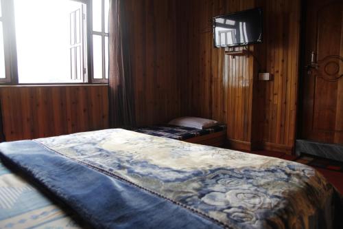 a bedroom with a bed and a television in it at Vamoose Sherpa Homestay in Ravangla