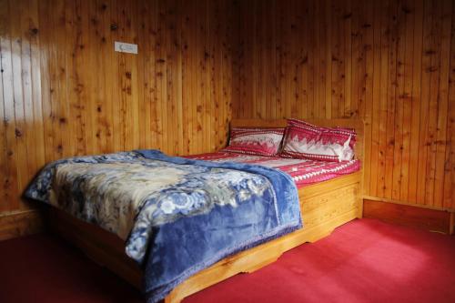 a bed in a room with wood paneled walls at Vamoose Sherpa Homestay in Ravangla