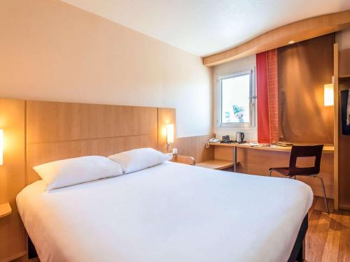 a bedroom with a large white bed and a desk at Ibis Château-Thierry in Essômes-sur-Marne
