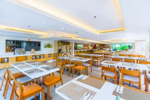 un restaurante con mesas y sillas y una cocina en HARRIS Hotel Kuta Galleria - Bali, en Kuta
