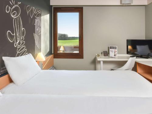 a bedroom with a large white bed and a window at ibis Charleroi Airport Brussels South in Charleroi