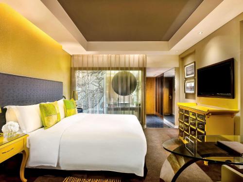a bedroom with a large white bed and a television at Sofitel Zhengzhou International in Zhengzhou