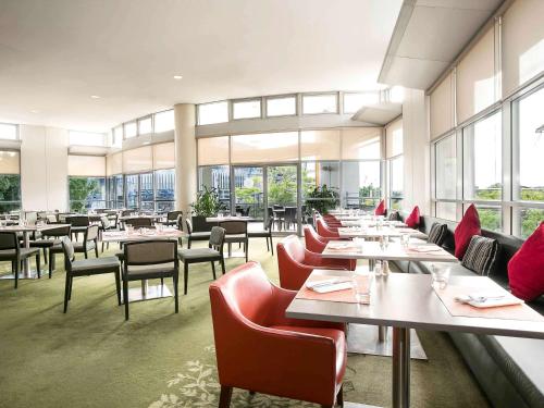 a restaurant with tables and chairs and windows at ibis Sydney Olympic Park in Sydney