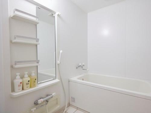 a white bathroom with a mirror and a sink at Hotel Familio Minakami in Minakami