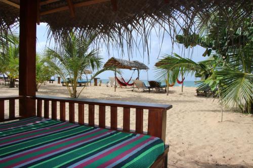 a bench on the beach with chairs and umbrellas at Shiva's Beach Cabanas in Tangalle
