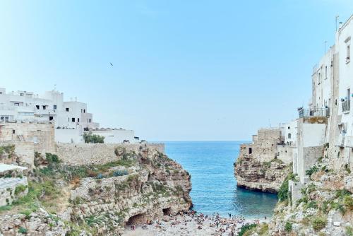 a group of people on a beach next to the ocean at POSEA - Polignano Sea Suites in Polignano a Mare