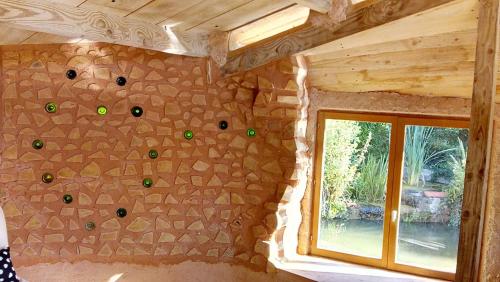 Cette chambre est dotée d'un mur en pierre et d'une fenêtre. dans l'établissement Cabanes de moon, à Moon-sur-Elle