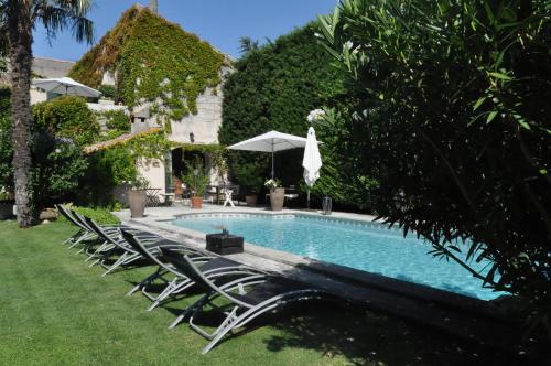 a swimming pool with chairs and an umbrella at La demeure in Eyguières