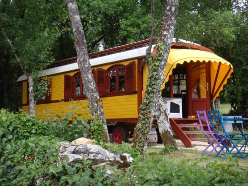un bus jaune et blanc garé dans les bois dans l'établissement les roulottes du LOT, à Gramat