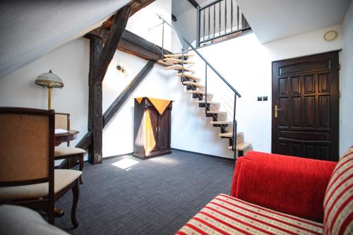 a living room with a staircase and a red couch at Gospoda pod Czarnym Łabędziem in Rydzewo