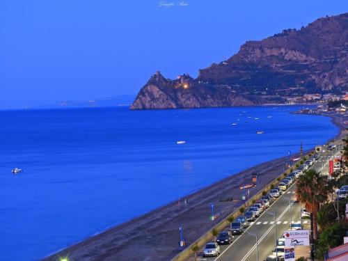 a view of a beach and the ocean at night at Villa dei Marchesi Carrozza in Santa Teresa di Riva