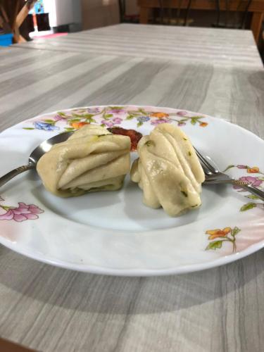 a plate of dumplings on a table with a fork and knife at Vamoose Sherpa Homestay in Ravangla