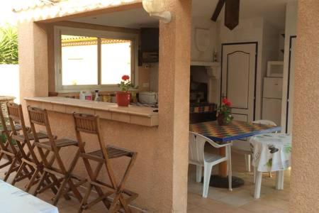 eine Küche mit einer Theke, einem Tisch und Stühlen in der Unterkunft Le Mas Des Oliviers in Agde