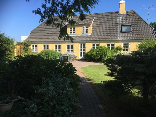 a yellow house with a pathway in front of it at Thurø Rev Guesthouse in Svendborg