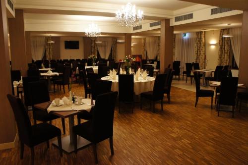 a dining room with tables and chairs and a chandelier at Hotel Camelot in Szczawno-Zdrój