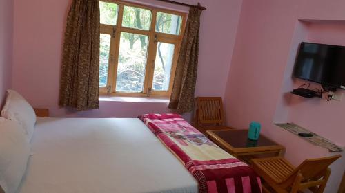 a bedroom with a bed and a window and a tv at Cottage Mini For Backpackers & Small Family in Manāli