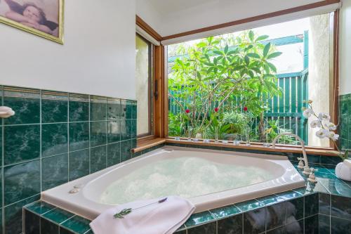 a bath tub in a bathroom with a window at Country Pleasures Bed and Breakfast in Angaston