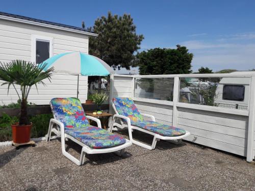 two chairs and an umbrella on a patio at Chalet Dalile IJmuiden aan Zee vlakbij het strand in IJmuiden