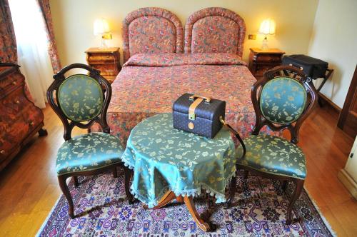 a bedroom with a bed with two chairs and a table at Park Hotel Villa Giustinian in Mirano