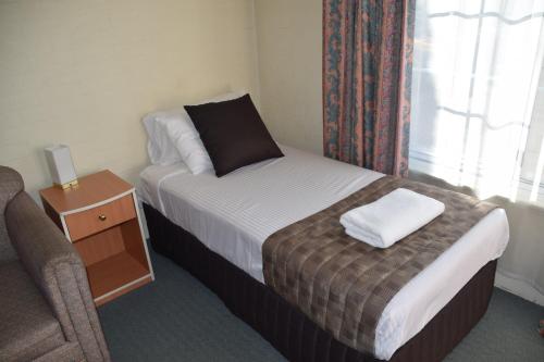 a hotel room with a bed and a chair and a window at Best Western Coachman's Inn Motel in Bathurst