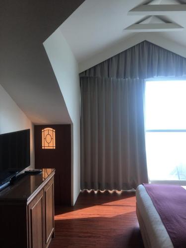 a bedroom with a bed and a tv and a window at Harmony Ocean Hotel in Kenting