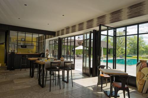 a dining room with tables and chairs and a pool at Manoir des Logis in Yvré-lʼÉvêque