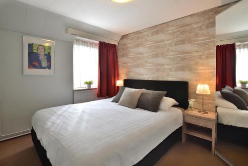 a bedroom with a large white bed and red curtains at Hotel Schilberg in Slenaken