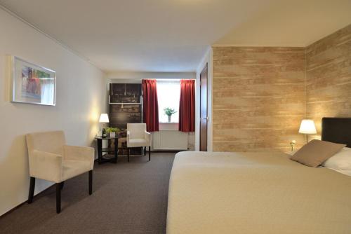 a hotel room with a bed and a table and chairs at Hotel Schilberg in Slenaken