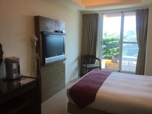 a hotel room with a bed and a flat screen tv at Harmony Ocean Hotel in Kenting