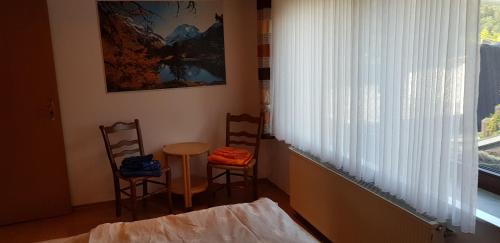 ヴィンターベルクにあるFerienwohnung Haus Kapellenblickの椅子2脚、テーブル、窓が備わる客室です。