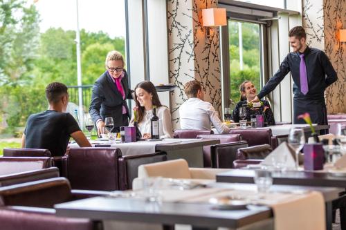 a group of people sitting at tables in a restaurant at Van der Valk Hotel Düsseldorf in Düsseldorf